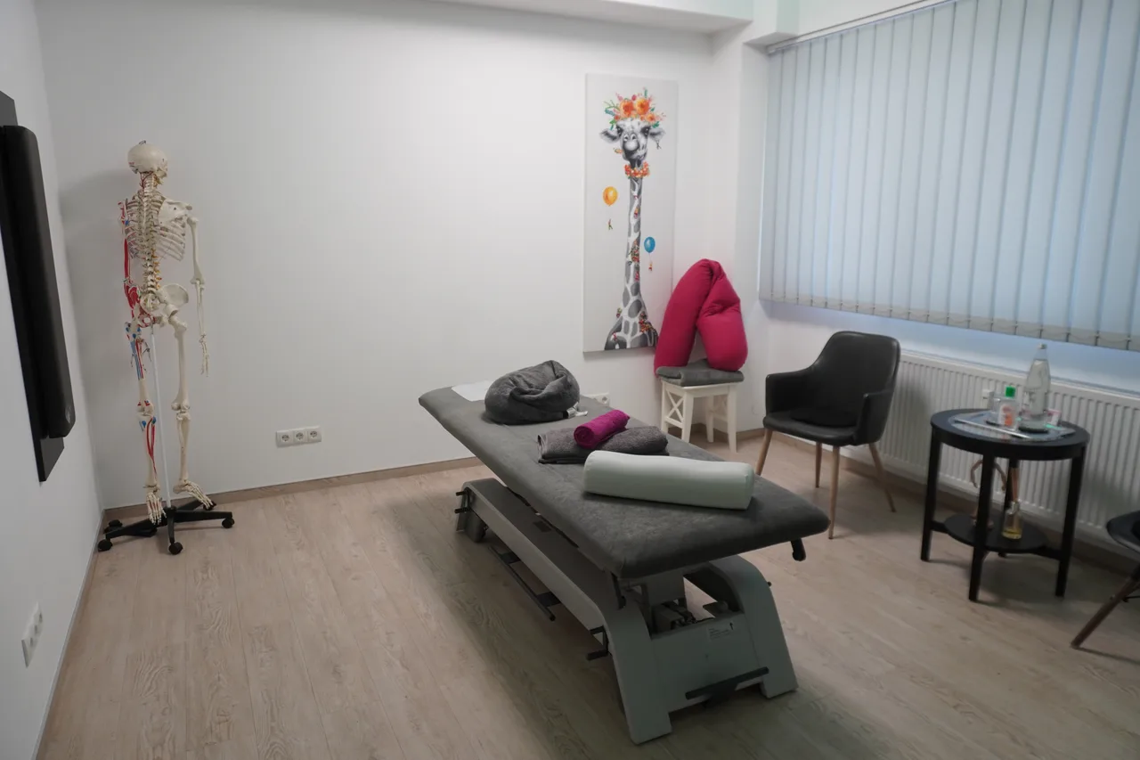 Behandlungsraum mit grauer Therapieliege und anatomischem Skelettmodell